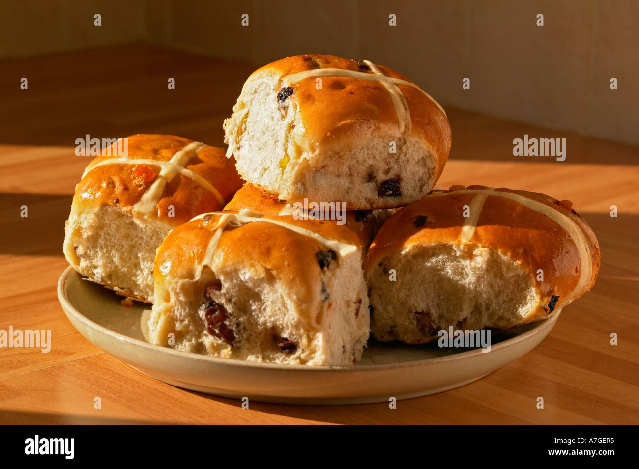 five hot cross buns on a plate in evening light Stock Photo