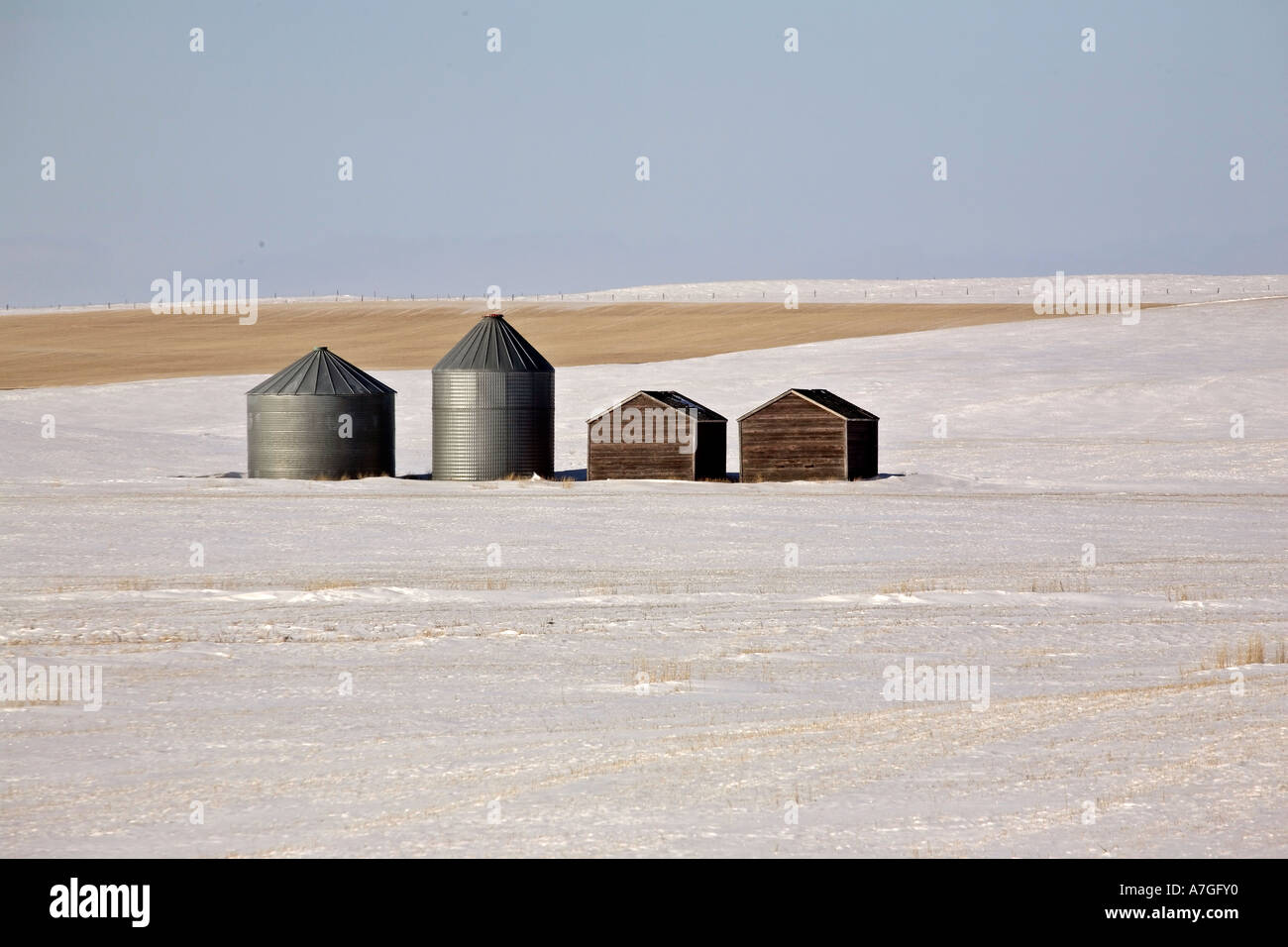 Old and new grain bins in a snow covered field in scenic Saskatchewan