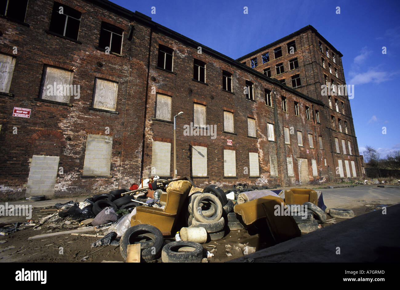 rubbish dumped on wasteground by derelict mill building leeds yorkshire
