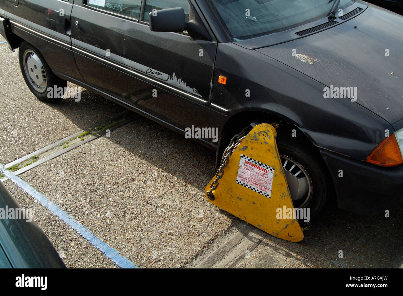 Wheel clamp on a parked car attached to one of the front wheels Parking offence England UK Stock