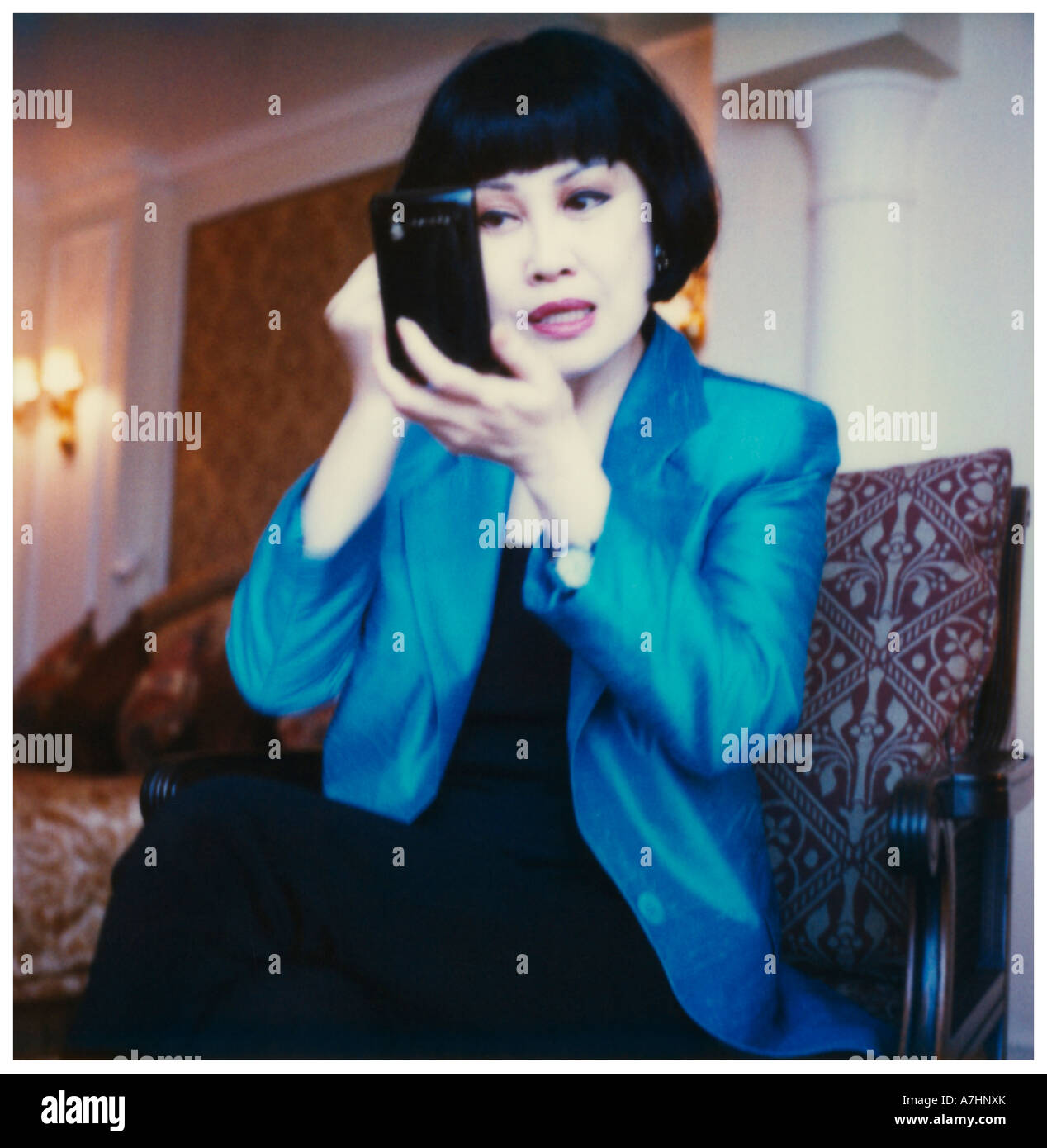 A Chinese woman putting on her make up in a bedroom Stock Photo