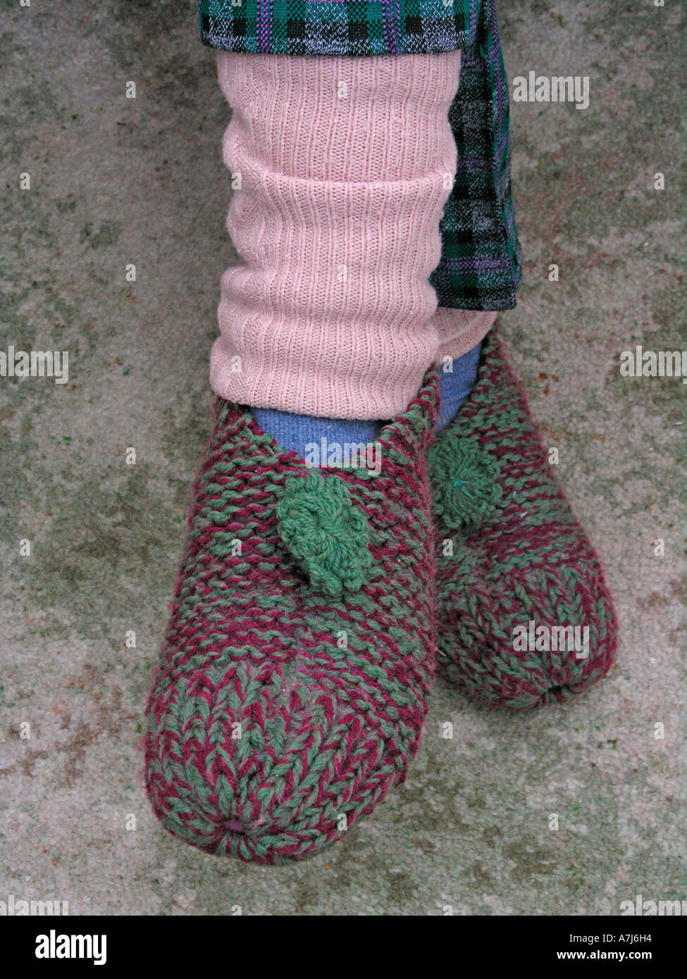elderly woman wearing leg warmers and knitted slippers to keep warm and cosy in winter Stock