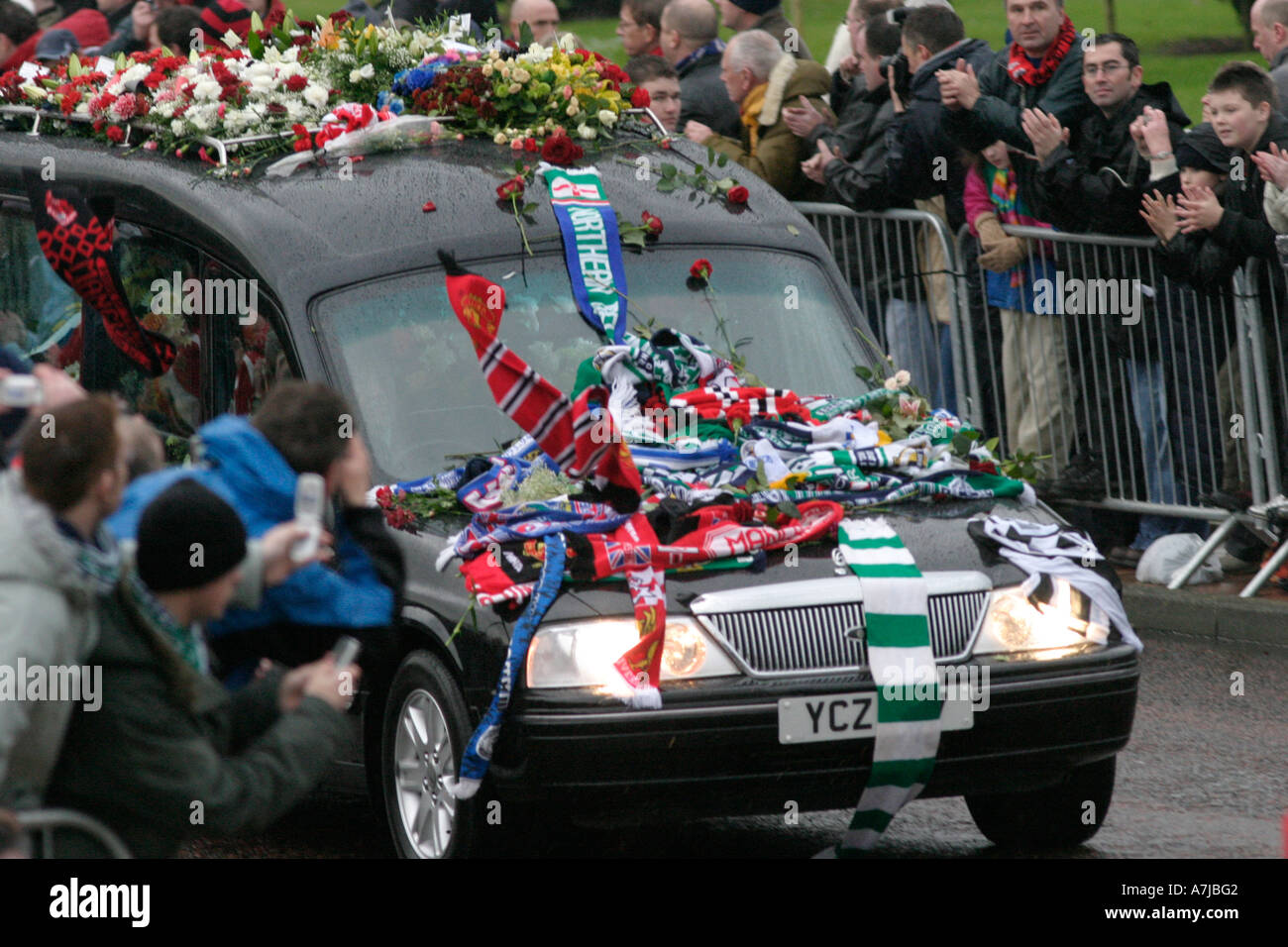 Mourners throw scarves onto the funeral car Bests funeral Belfast Northern Ireland Stock