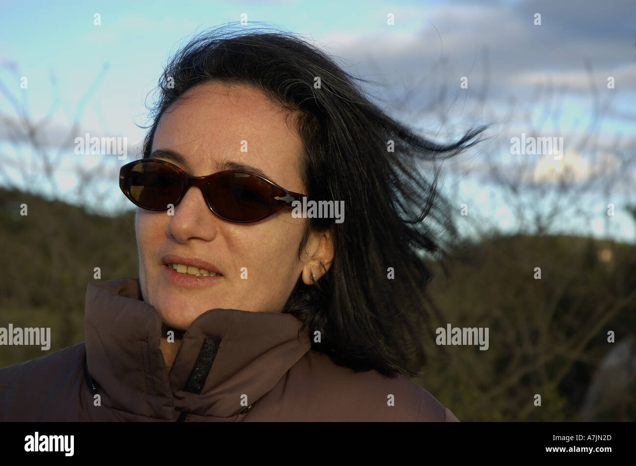 Portrait of a woman wearing sunglasses on a windy day. Stock Photo