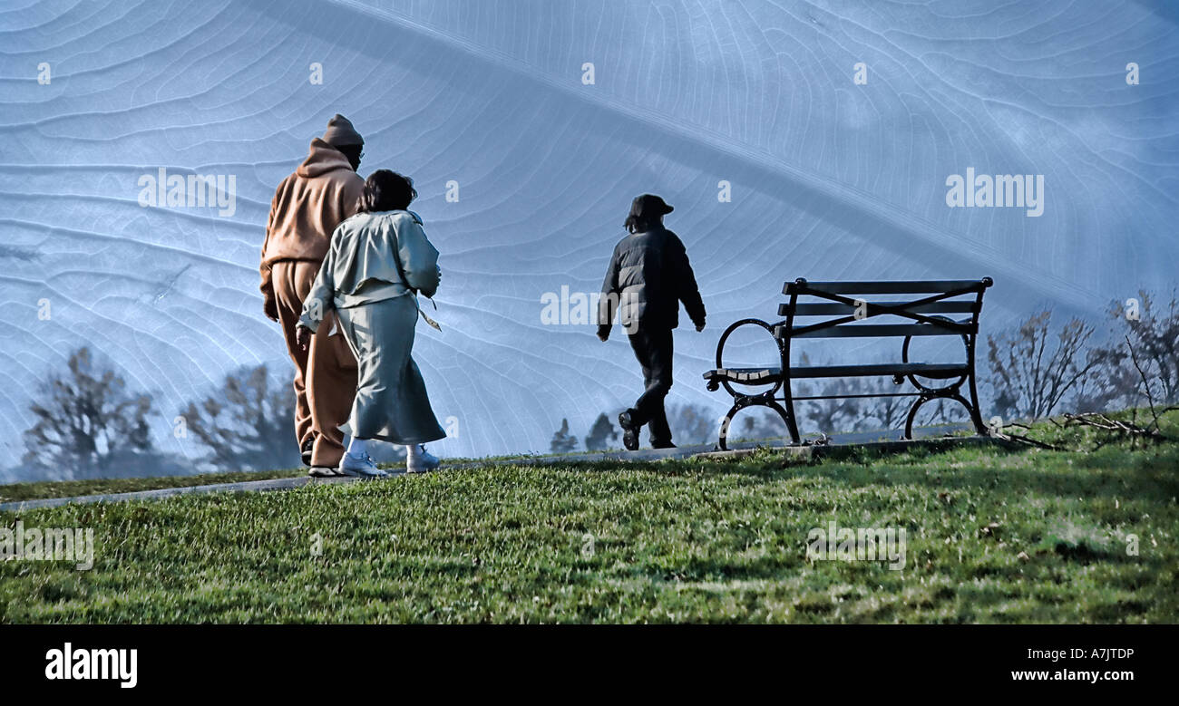three African American people walking through a park passing by a bench exercising in the morning Stock Photo