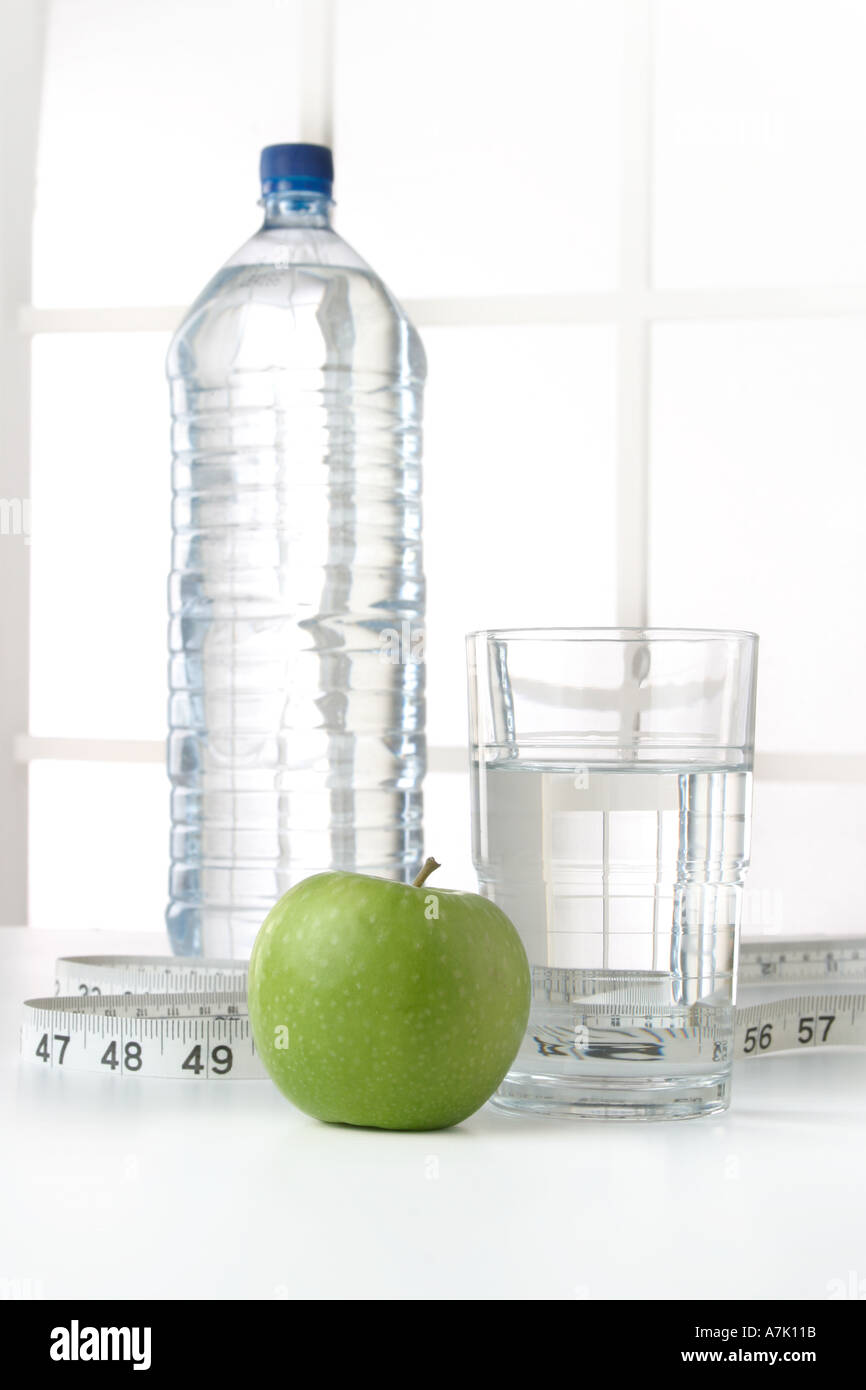 PORTRAIT SHOT OF A BOTTLE OF WATER WITH A GLASS OF WATER AND AN APPLE WITH MEASURING TAPE Stock Photo