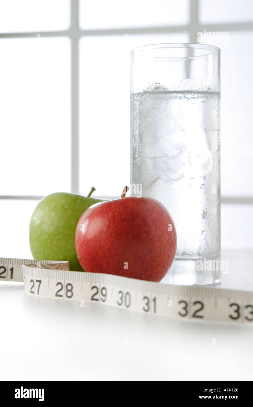 PORTRAIT SHOT OF  A GLASS OF WATER AND TWO APPLES ONE RED AND ONE GREEN WITH MEASURING TAPE Stock Photo