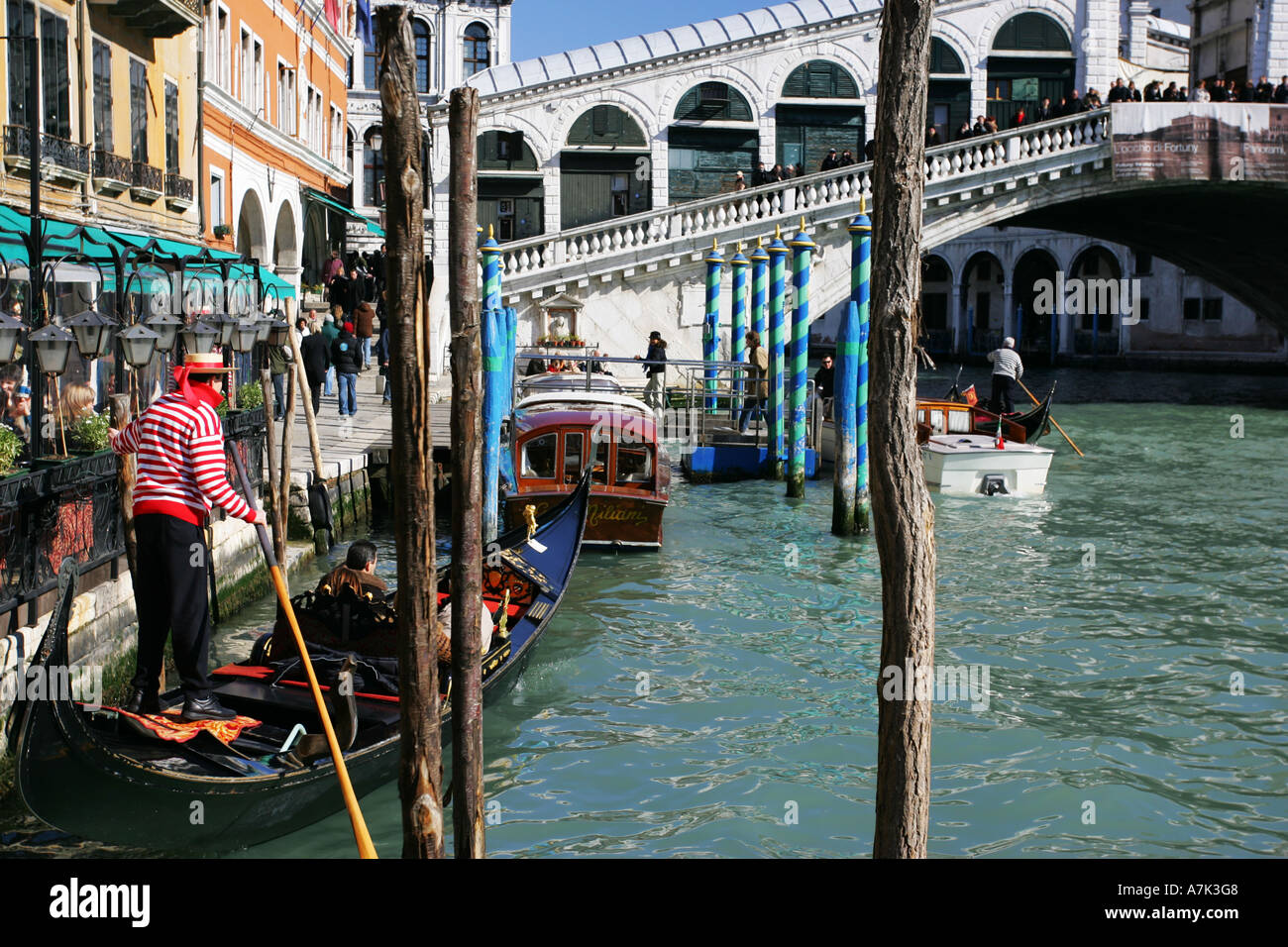 Typical Venice scene as a tourist laiden gondola departs from a cafe near the famous Rialto Bridge Venice Italy Europe EU Stock Photo