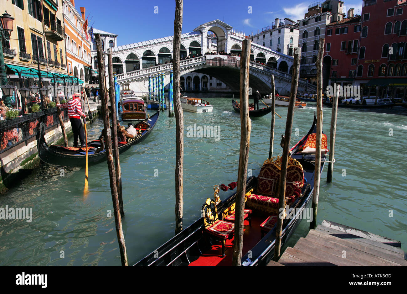 Typical Venice scene as a tourist laiden gondola departs from a cafe near the famous Rialto Bridge Venice Italy Europe EU Stock Photo