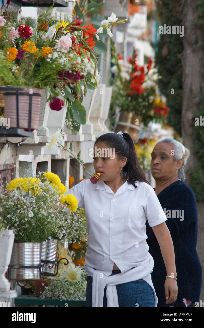 A Mexican girl and grandmother put flowers on a grave during the DEAD OF THE DEAD SAN MIGUEL DE ALLENDE MEXICO Stock Photo