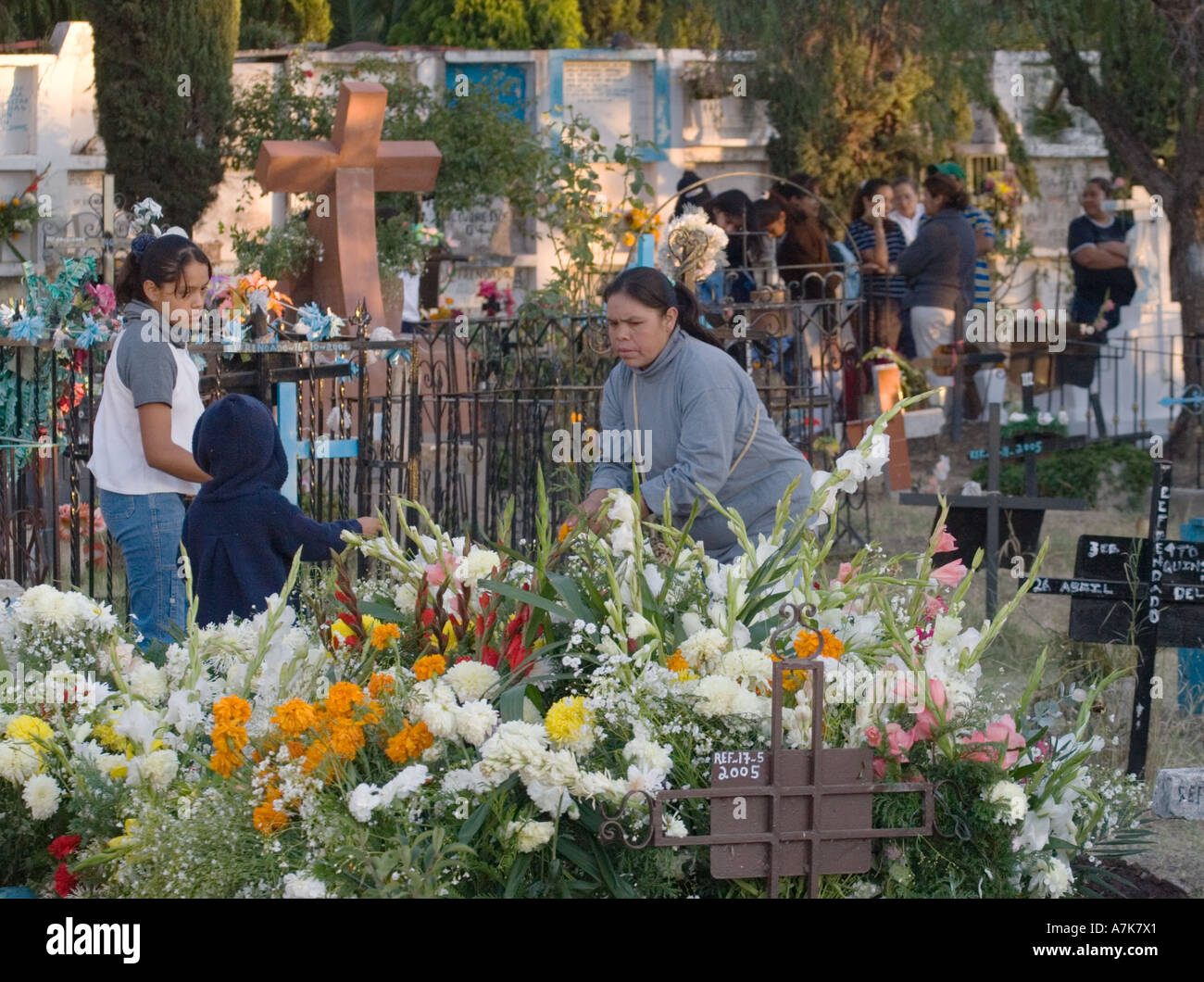 A Mexican family covers a relatives grave with flowers during the DEAD OF THE DEAD SAN MIGUEL DE ALLENDE MEXICO Stock Photo