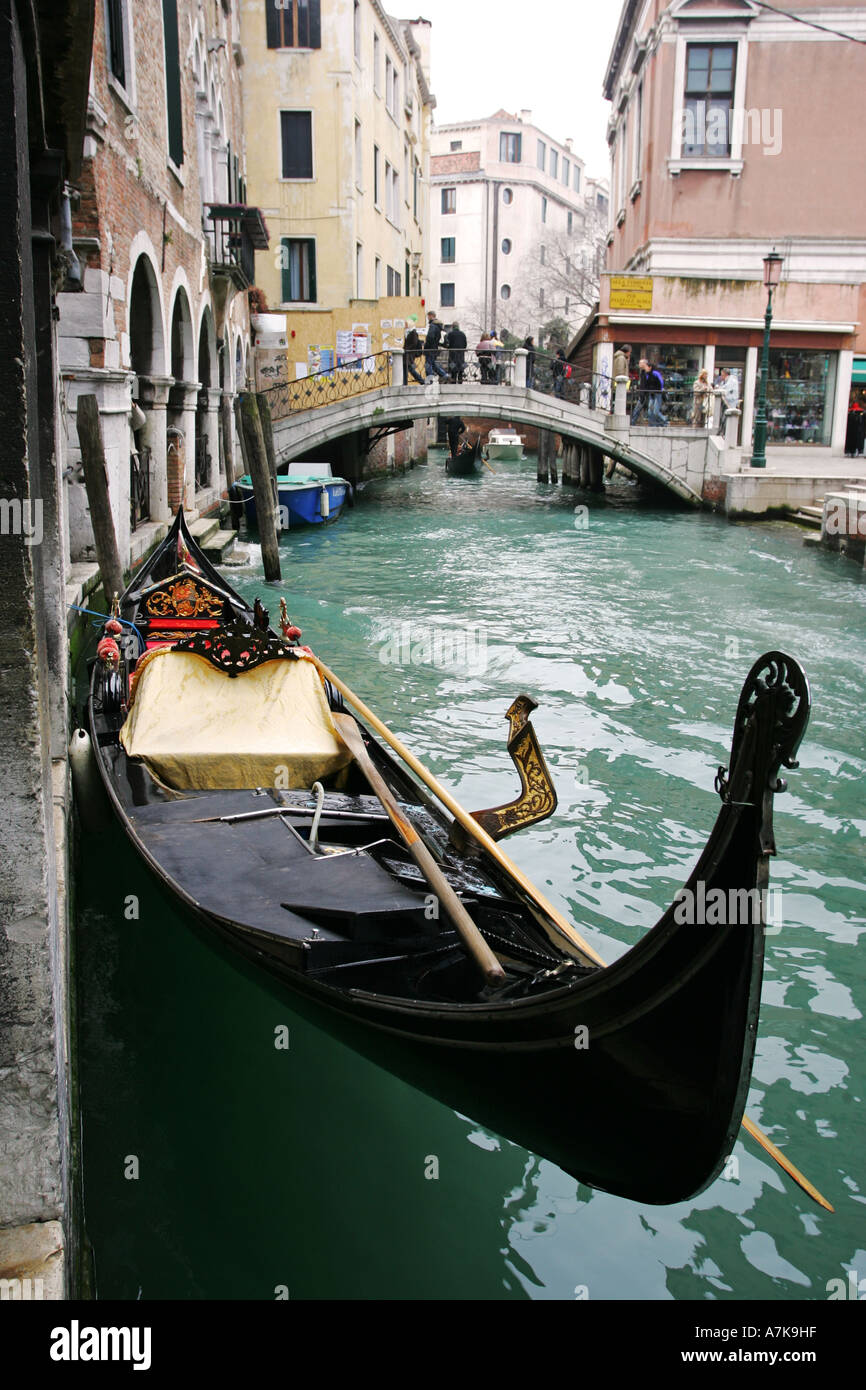 Typical Venetian image of famous gondola boat with stone pedestrian bridge emerald green canal Venice Italy Europe EU Stock Photo