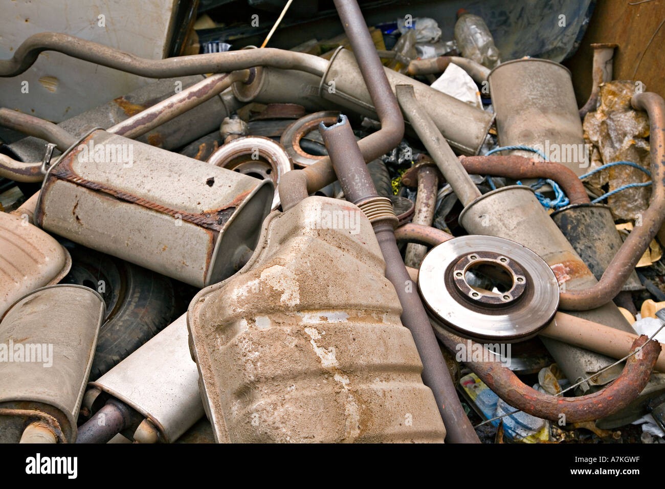 Car exhaust pipe silencers and brake disk in scrap heap for disposal at