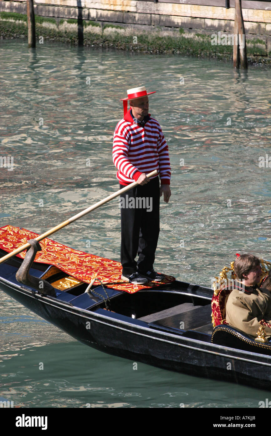 Closeup of typical Venetian gondola man in colourful uniform punting boat on Grand Canal Venice Italy european destination EU Stock Photo