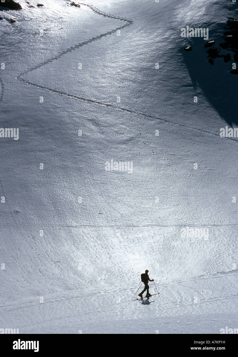 Backlight view of ski alpinist on a steep slope with zigzag ascending track in Tessin, Switzerland Stock Photo