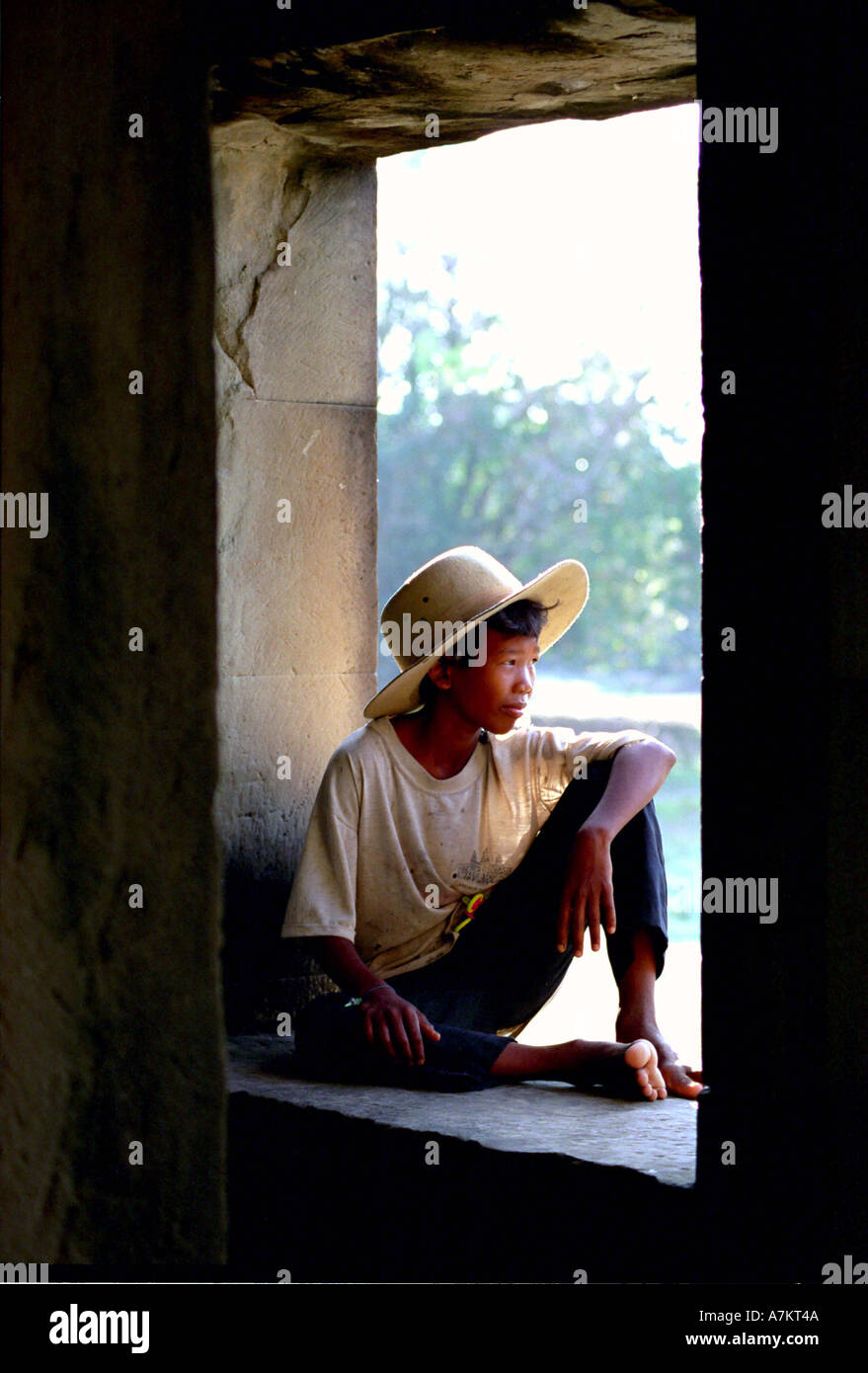 Boy sitting in the the window Ankor Wat Cambodia Stock Photo