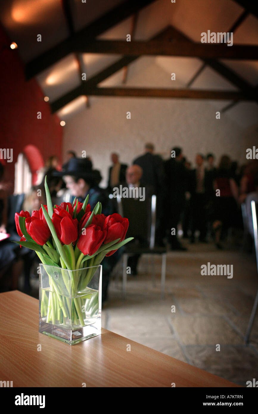 Bright Red Tulips In A Plain Glass Vase On A Table In A Room