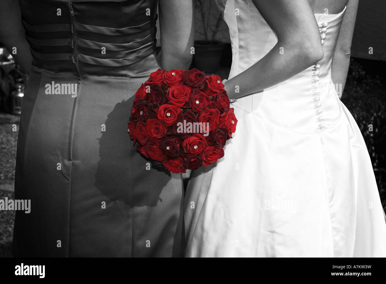 A bride and her bridesmaid in black and white with vibrant red rose flower  bridal bouquet in full colour modern reportage weddi Stock Photo - Alamy, image size:1300x956