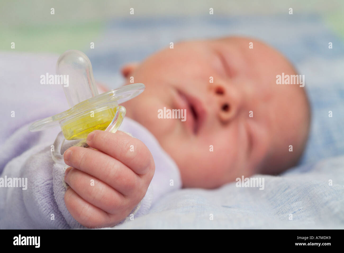 Newborn baby sleeping and holding pacifier Stock Photo Alamy