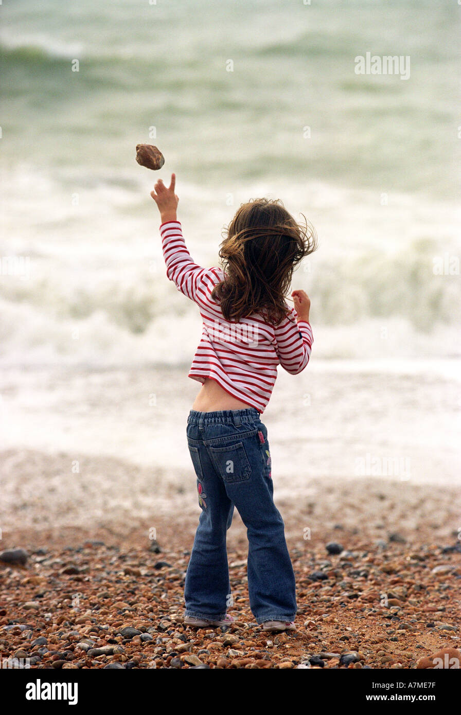 A small girl throwing stones into the sea Stock Photo Alamy