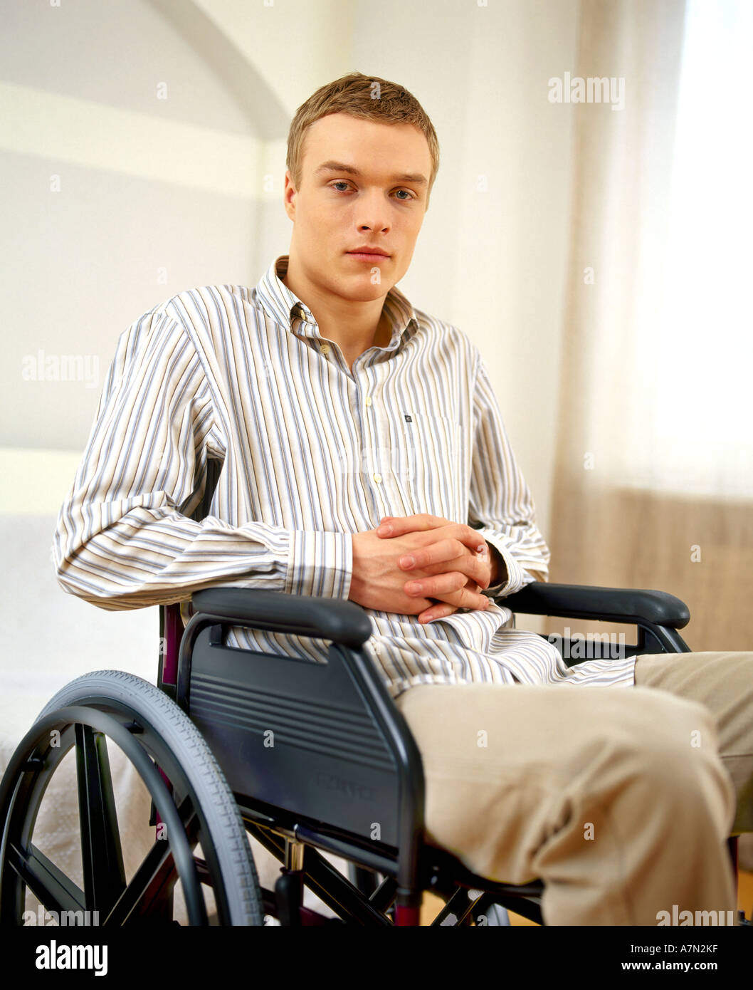 indoor flat room livingroom man young boy 20 25 blonde shirt stripe stripes  striped sit wheelchair invalid disabled rest rela Stock Photo - Alamy