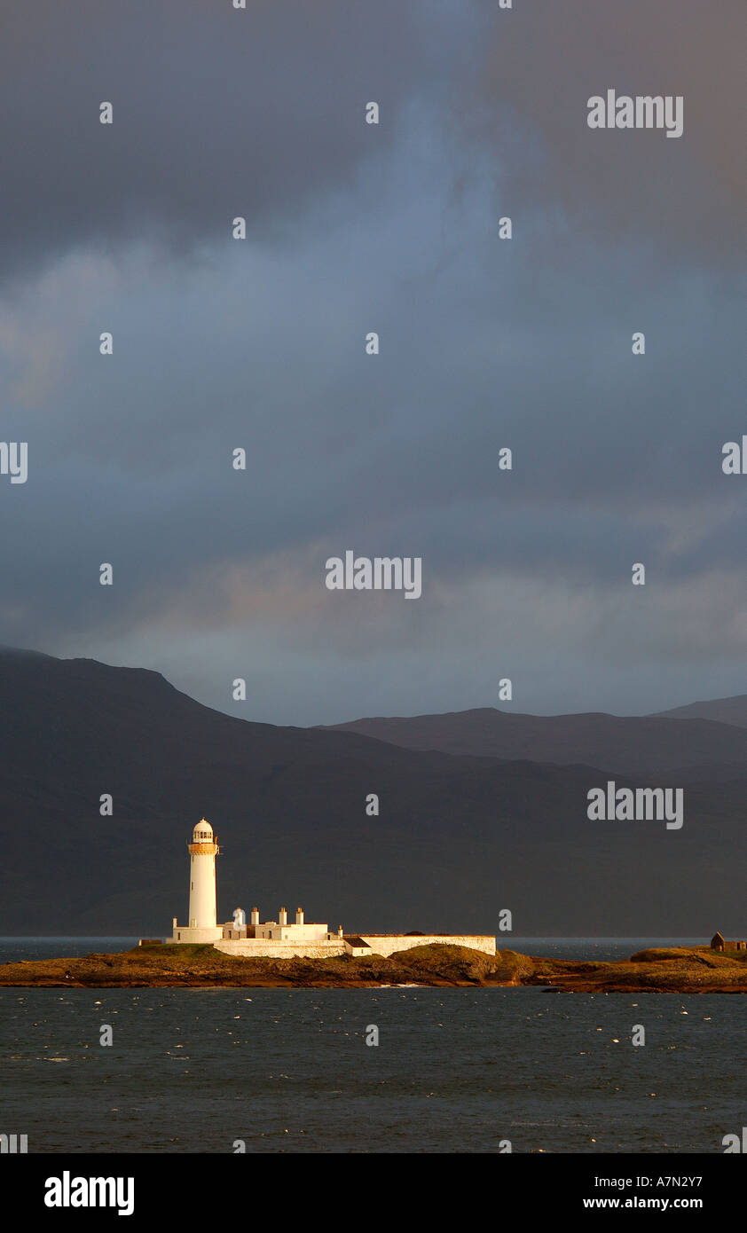 Lighthouse on Eilean Musdile in the Sound of Mull Western Isles Scotland in early morning sunlight with dark stormy clouds Stock Photo