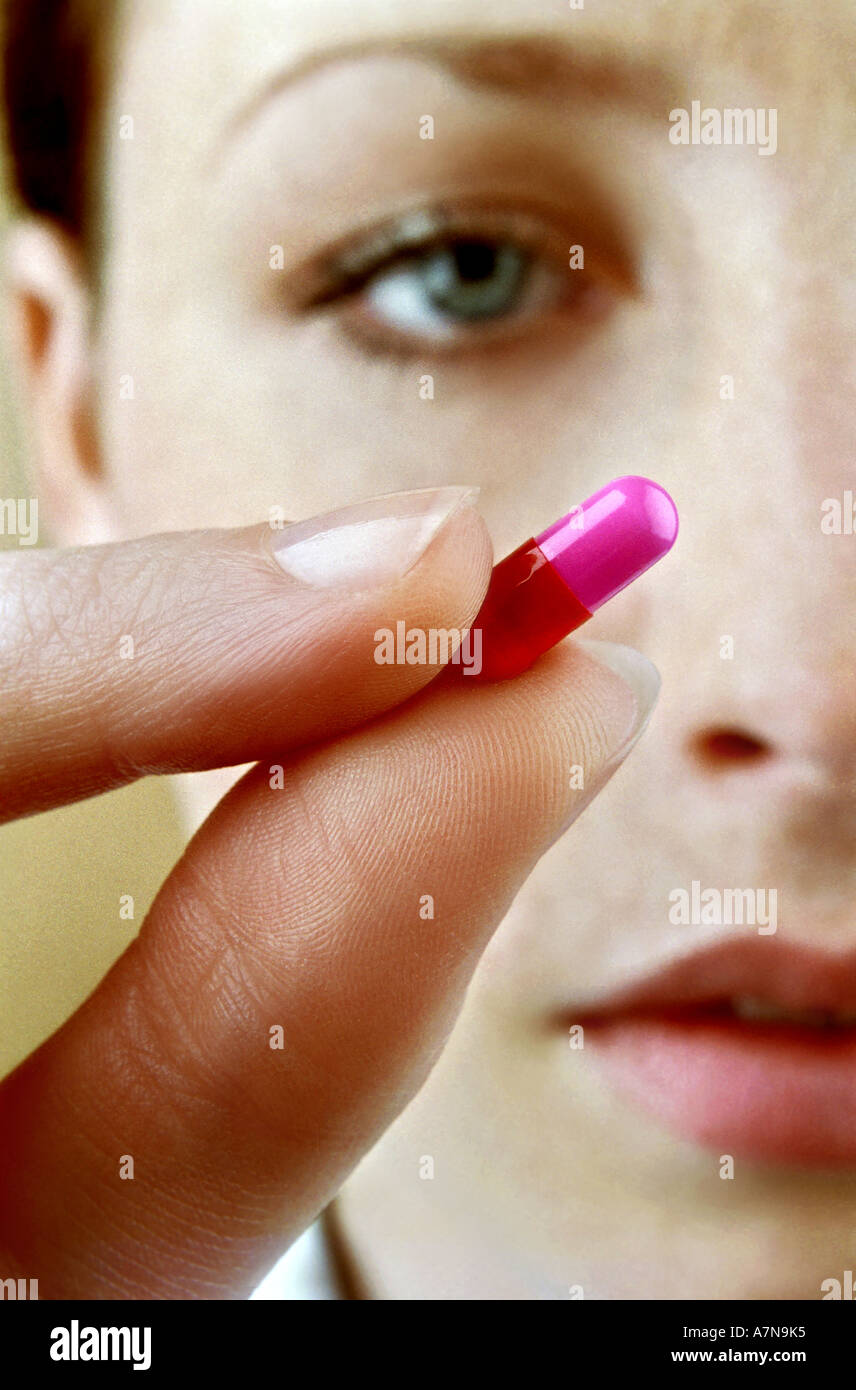 indoor studio woman young girl 20 25 face hold finger fingers pill tab tablette medicine remedy drug cure vitamine take bolt Stock Photo