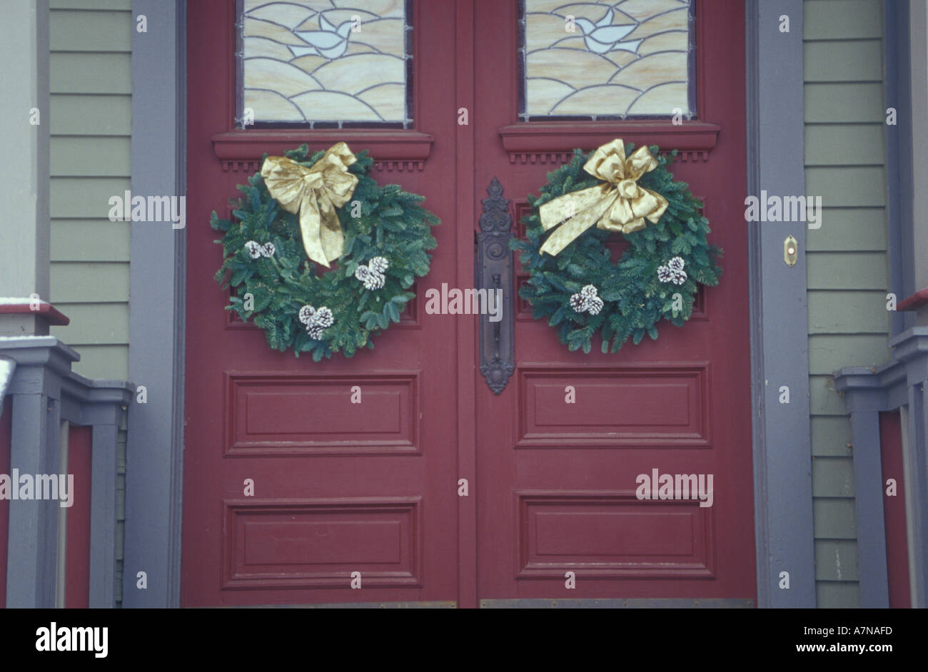 Two Christmas Wreaths Decorate The Double Doors Of An Old House In