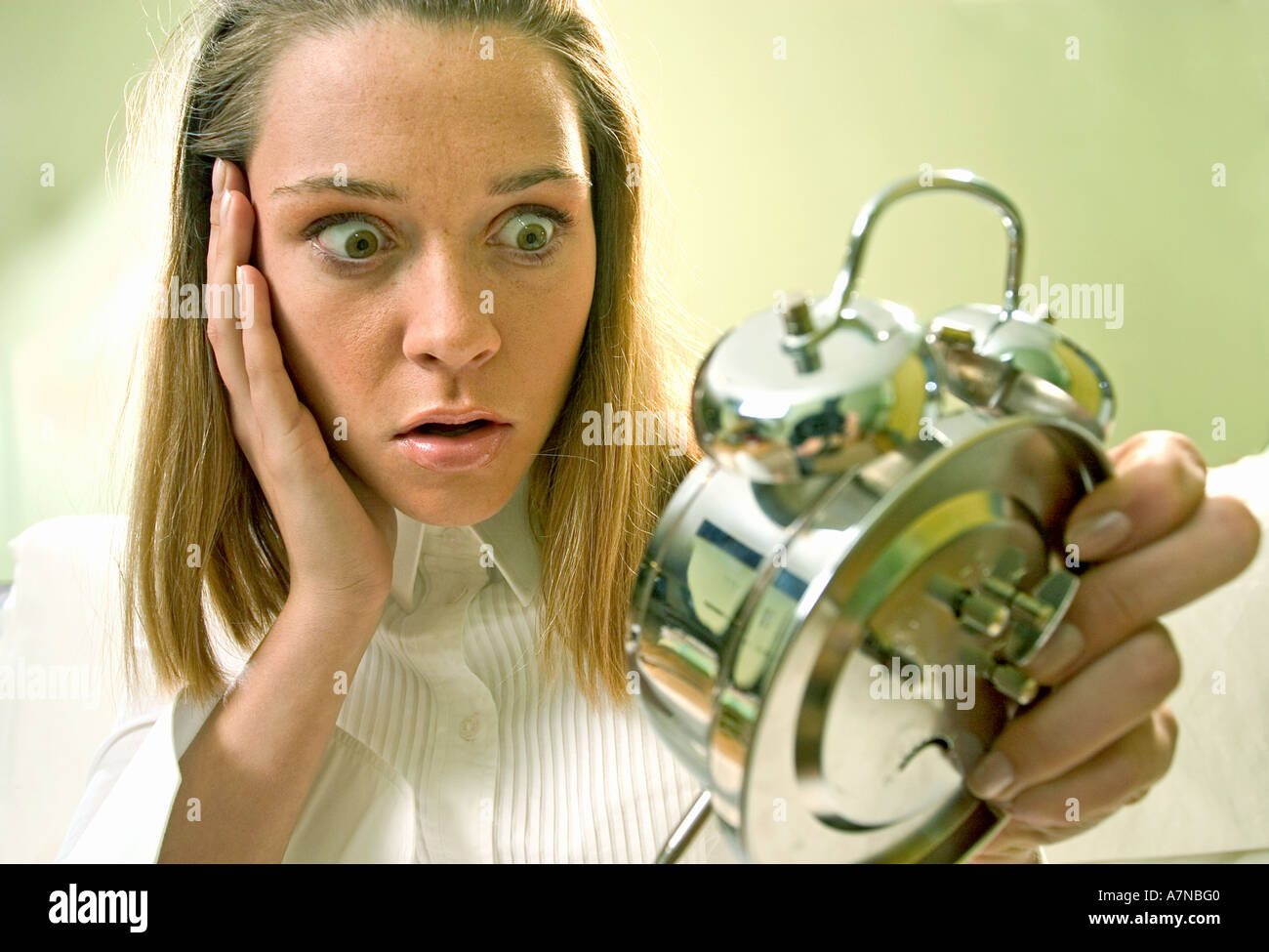 indoor flat room close up woman 25 30 young blonde wake up dream look clock alarm clock hour facial expression suprised appal Stock Photo