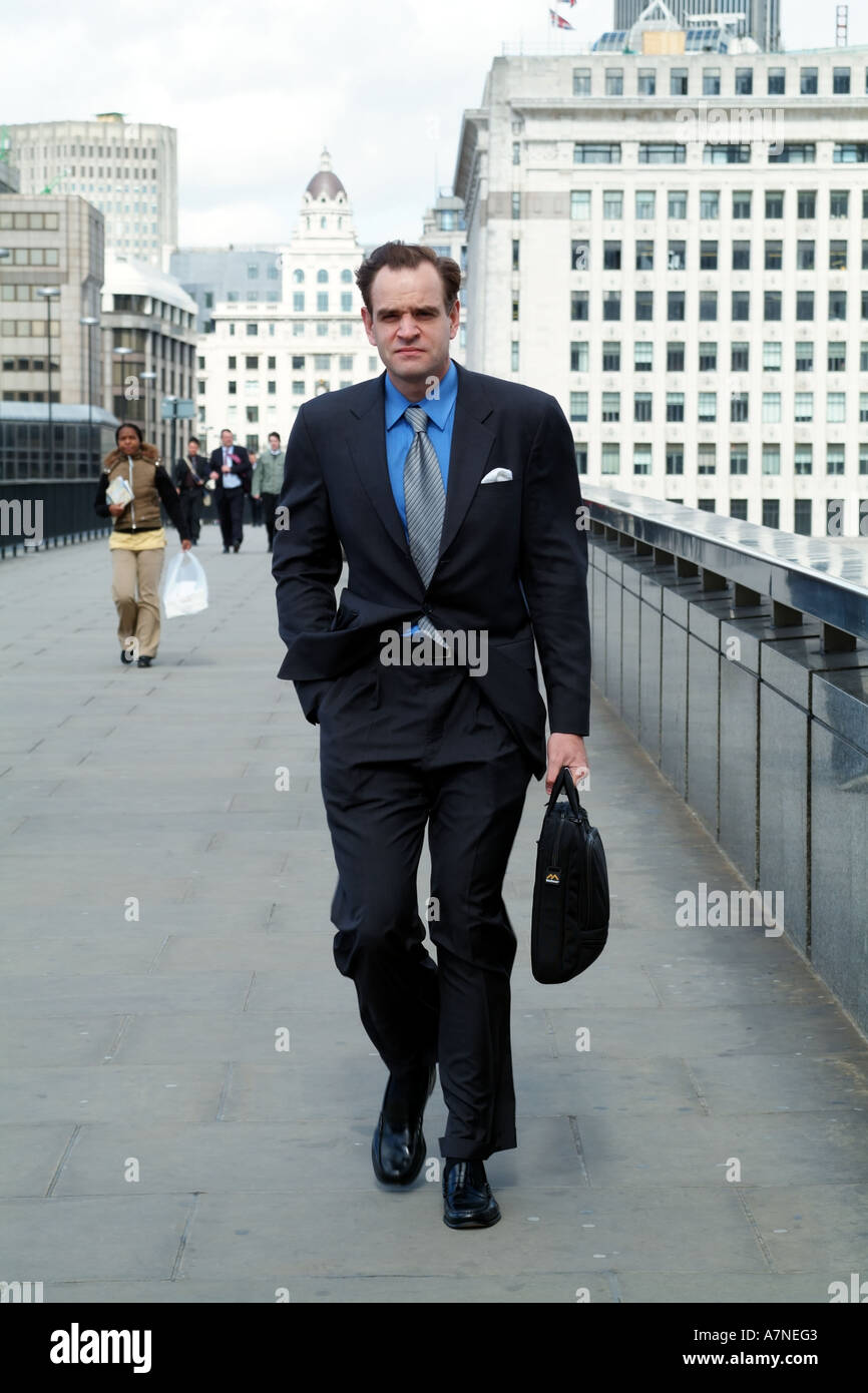 City gent holding briefcase walking on Millennium Bridge city of London England United Kingdom UK Stock Photo