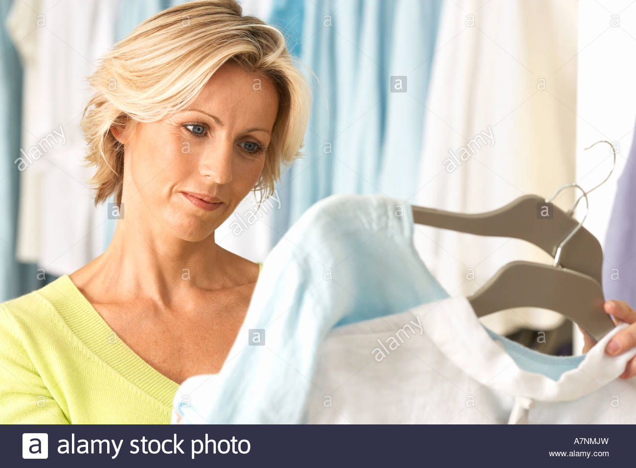 Mature Woman Shopping In Clothes Shop Comparing Two Tops On Coathangers Close Up Mature Woman Shopping In Clothes Shop Comparing Two Tops On Coathangers Close Up