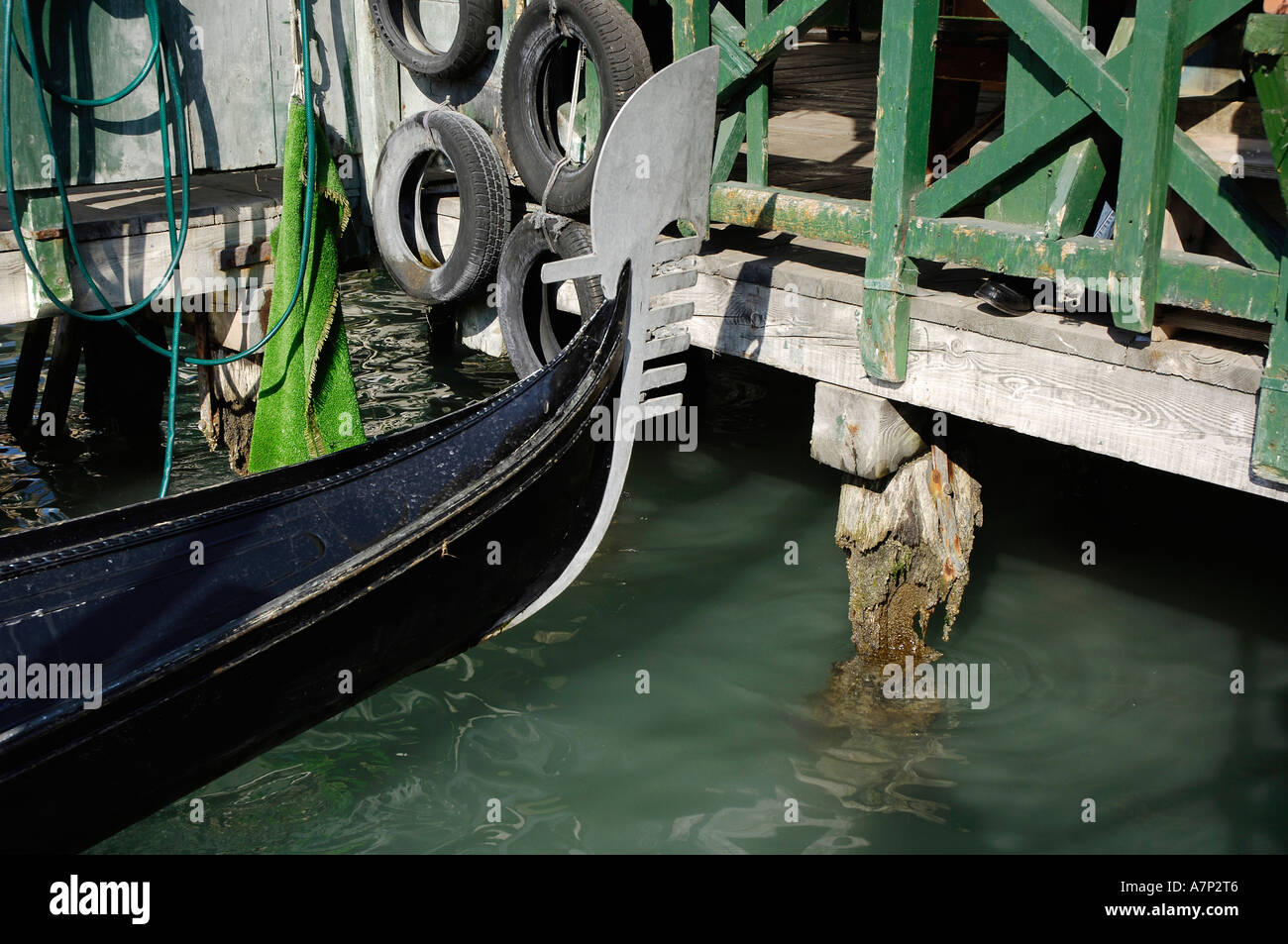 Gondola at boardwalk with rotten stilts in water, Venice, Italy Stock