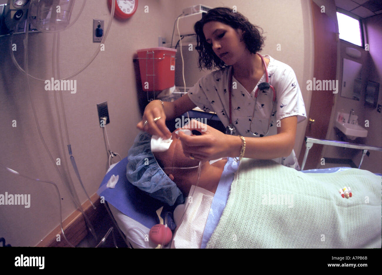 Female nurse putting eye drops in eyes of Hispanic male patient before