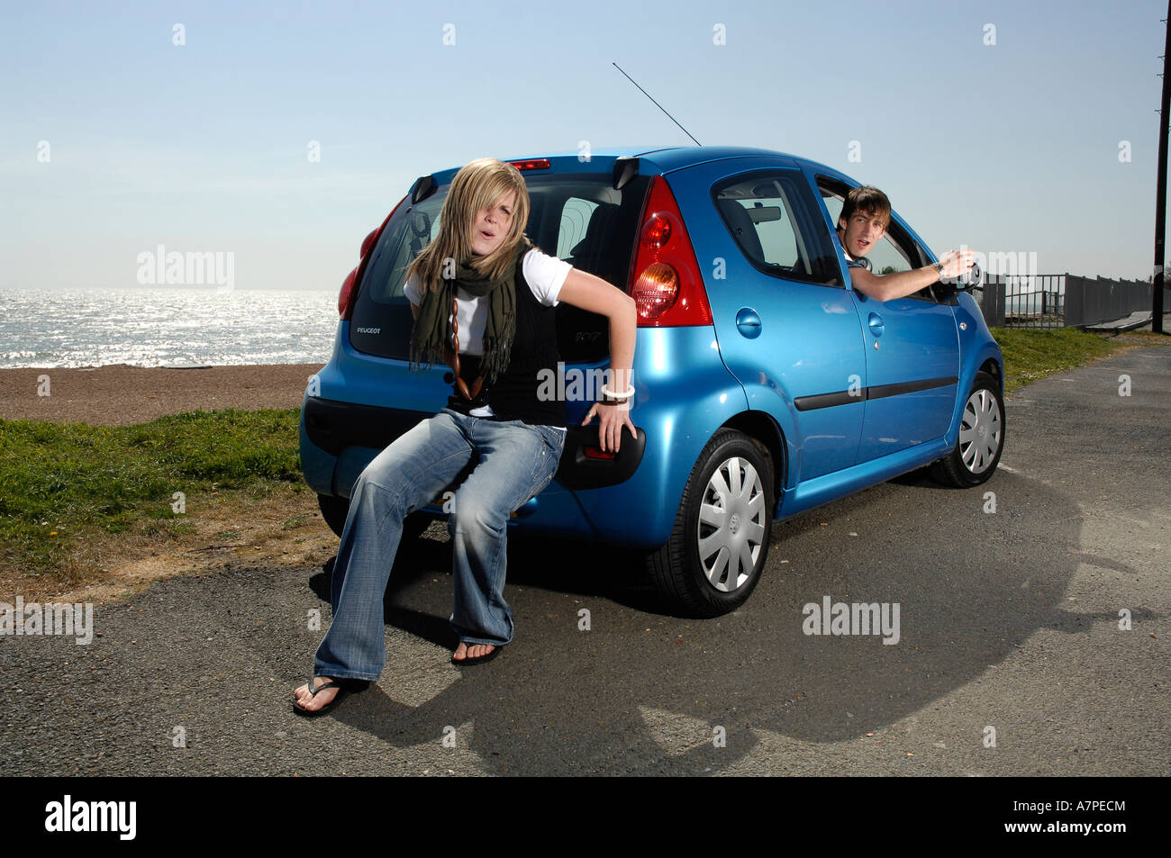 Young woman push starting a car while the man shouts encouragement