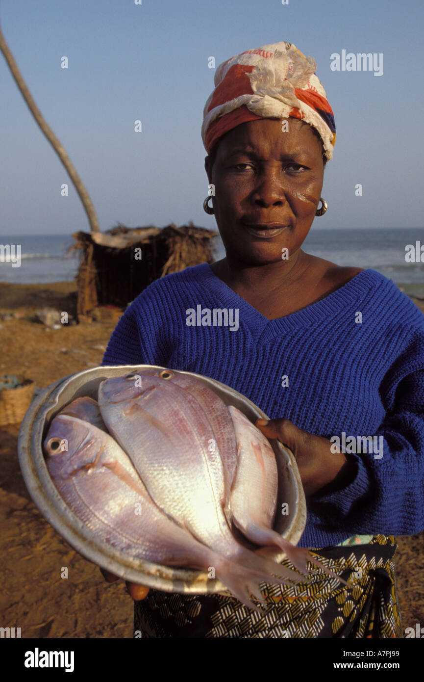 Ghana scarred fisher-woman sells freshly caught appetizing fish beside the beach at sunset African coast Stock Photo