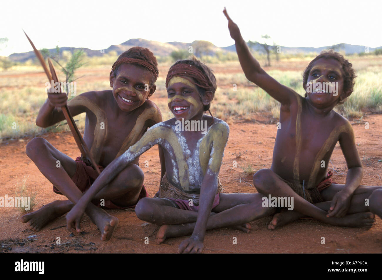 Happy Aboriginal boys painted up for ceremony play with boomerang in the desert south of Alice Springs Central Australia Stock Photo