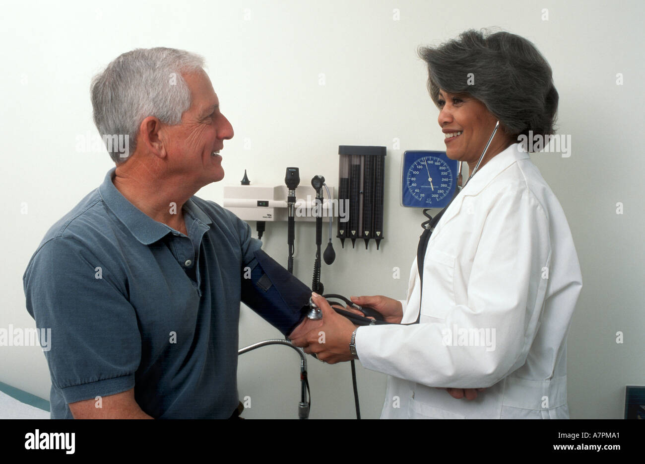 A doctor takes a patient s blood pressure during an office visit Stock