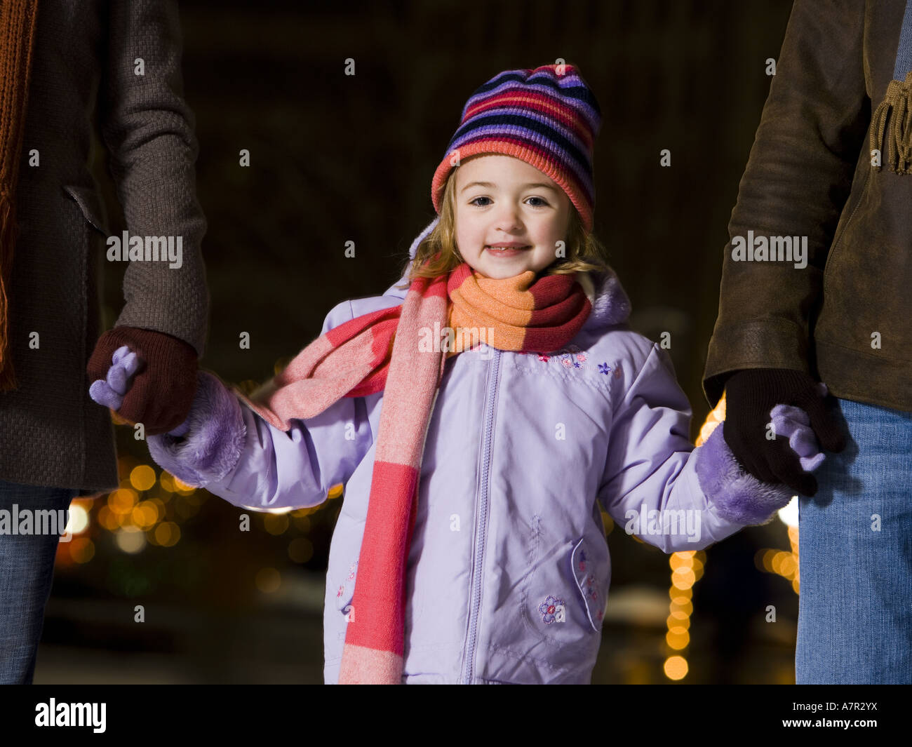 Girl outdoors in winter smiling holding hands with adults Stock Photo ...