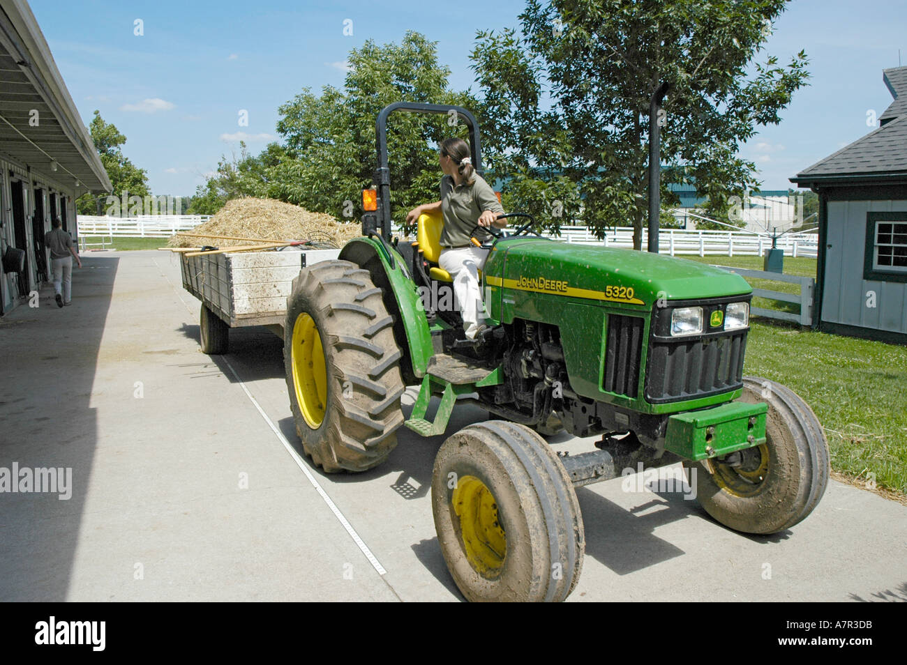 Employees at Kentucky Horse Park cleaning stables and removing horse waste with John Deer tractor, and full trailer of hay and droppings Stock Photo