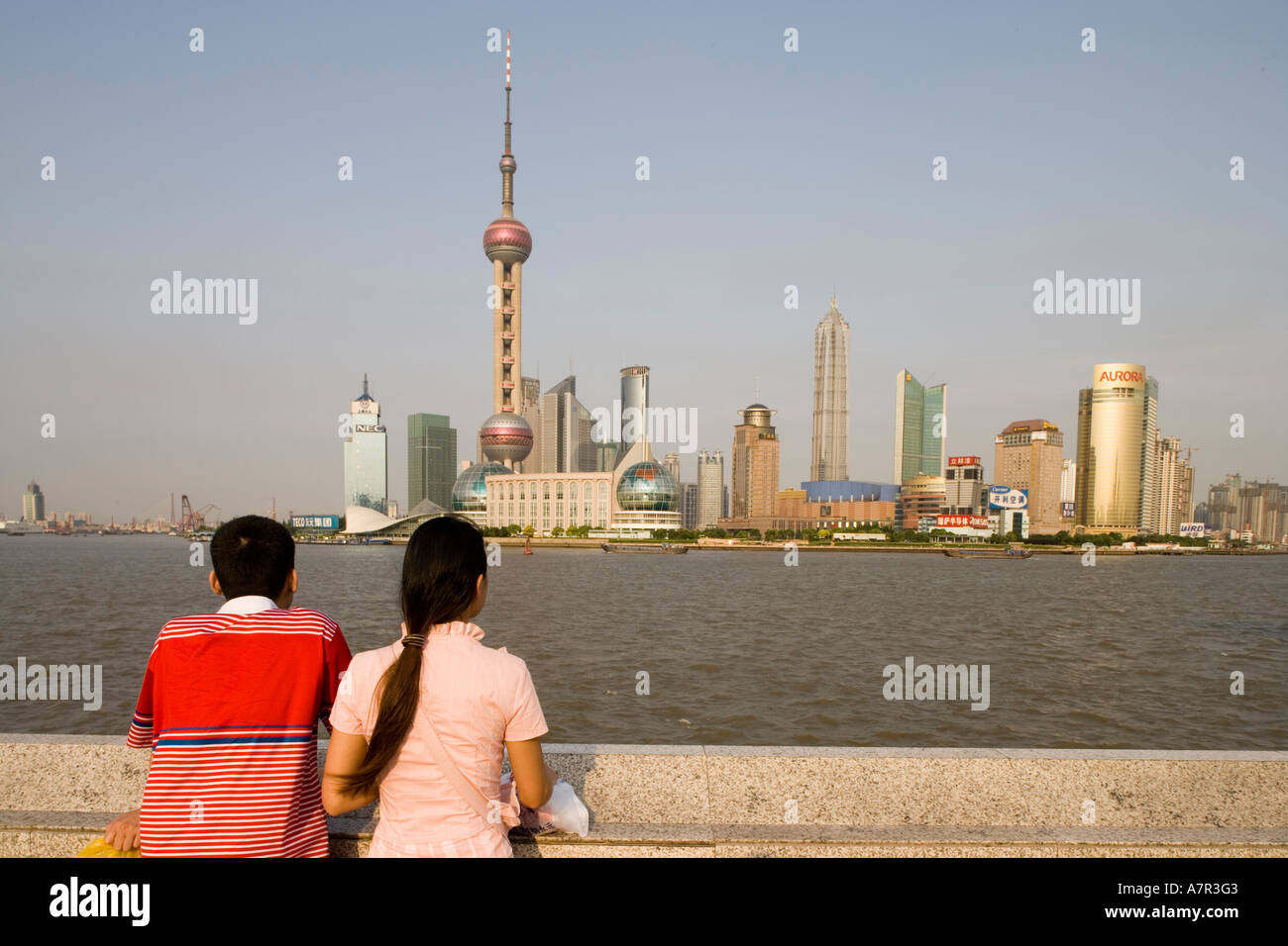 Asia China Shanghai Couple looks out at Oriental Pearl TV Tower and Pudong skyline along Huangpu River on summer afternoon Stock Photo