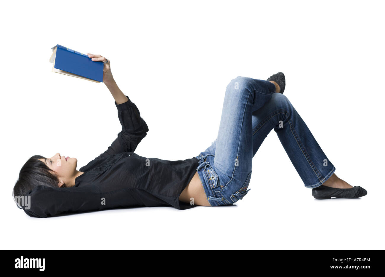 Woman lying down with hardcover book reading Stock Photo - Alamy