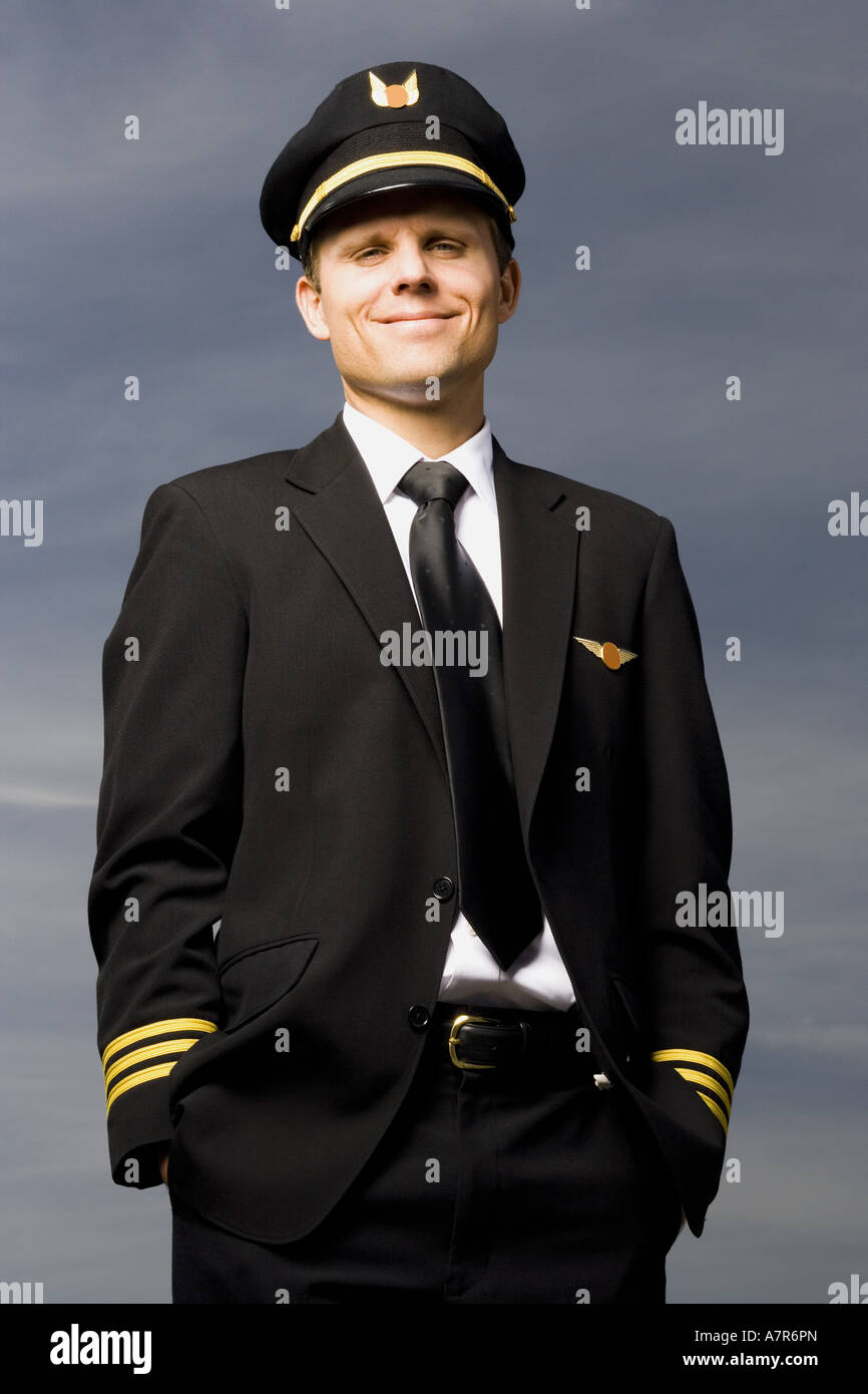 Pilot standing with hands in pockets smiling Stock Photo - Alamy