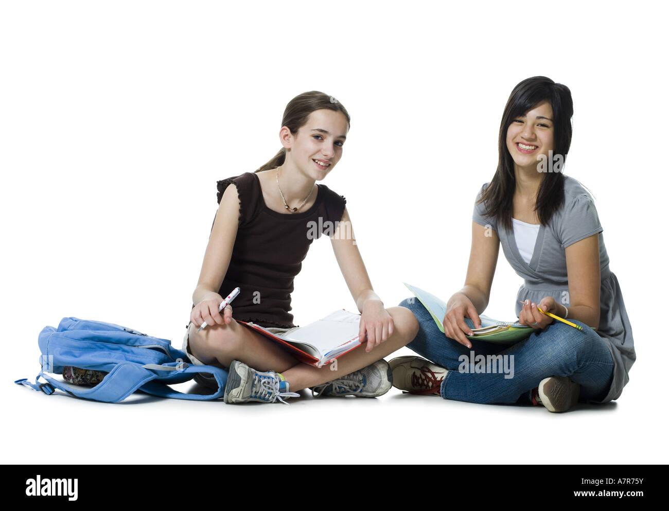 Two girls sitting cross legged doing homework Stock Photo - Alamy