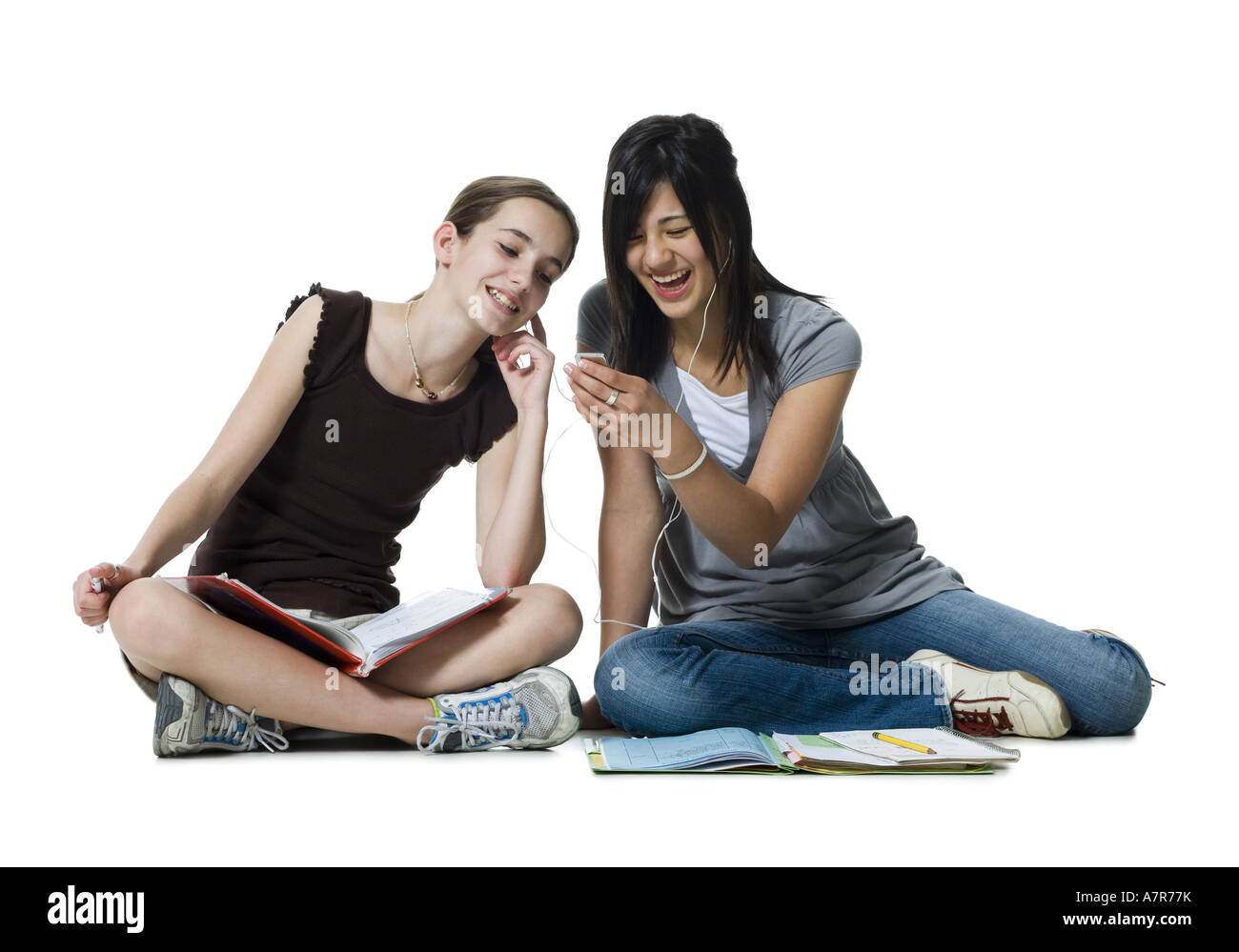 Two girls sitting cross legged with homework and mp3 player Stock Photo -  Alamy