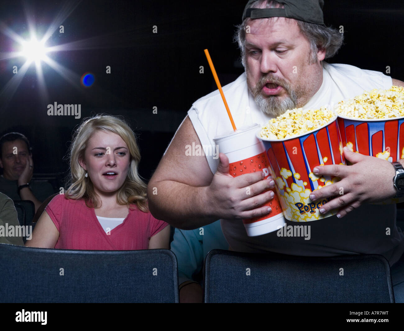 large man with buckets of popcorn and drink at movie theater stock