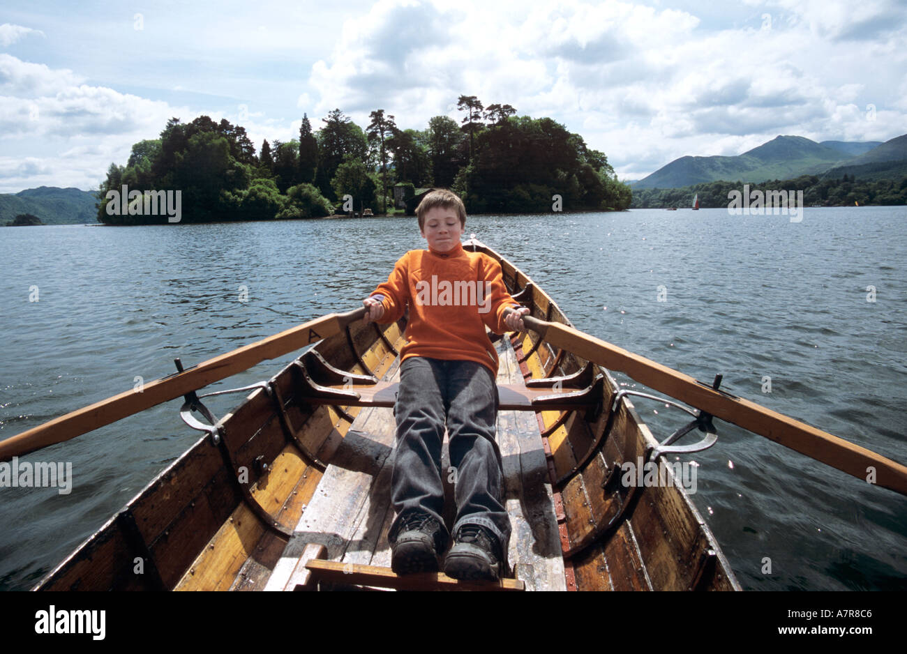 Boy aged ten rowing hired boat on Derwentwater with Derwent Isle in ...