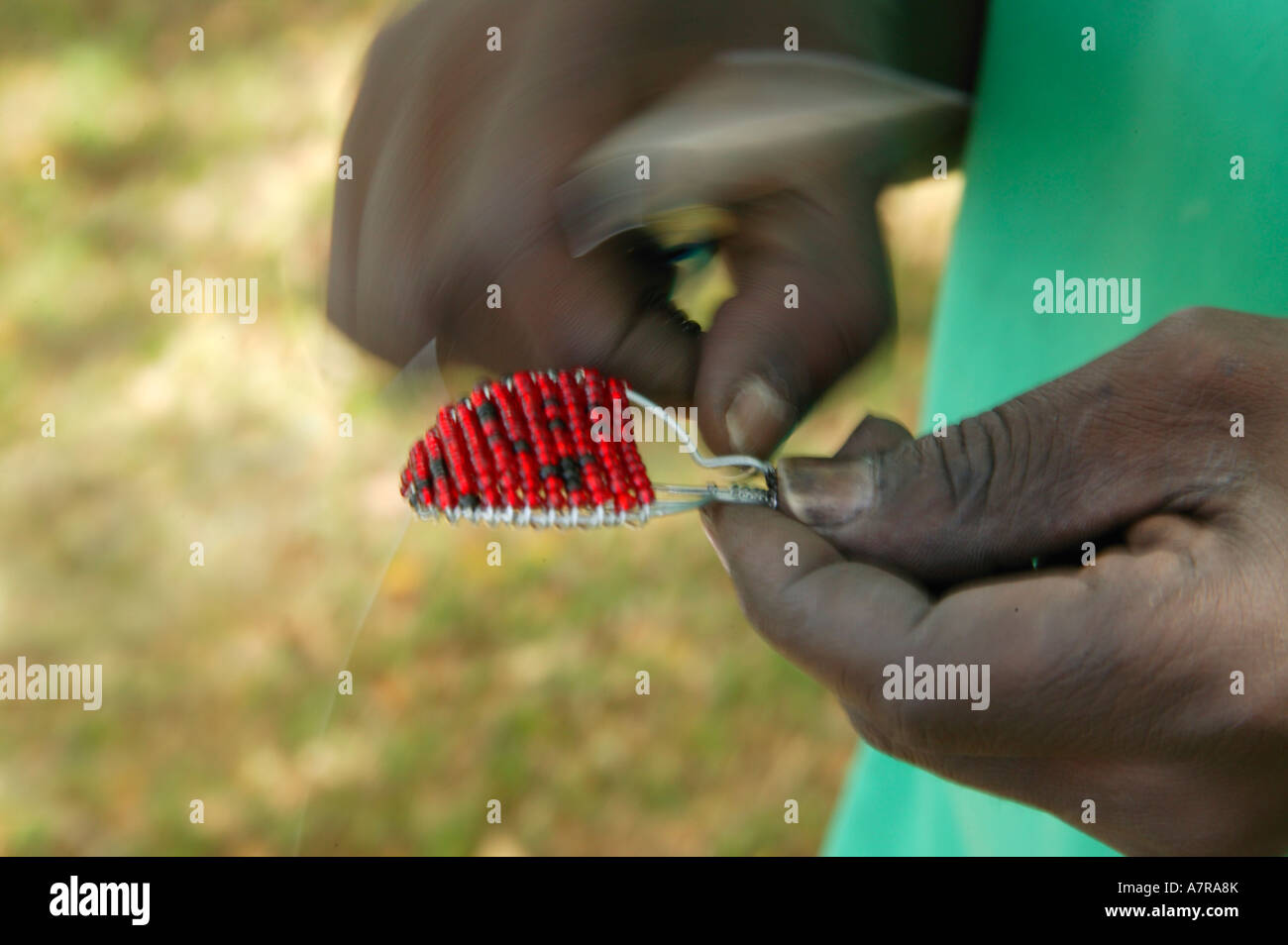 Close up of a man constructing a curio key ring from wire and colourful red beads Nelspruit Mpumalanga South Africa Stock Photo