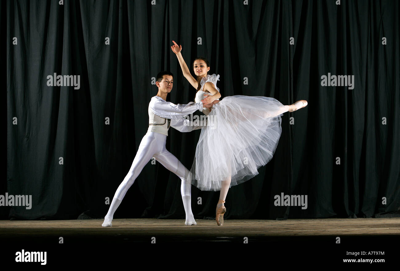 Boy and girl ballet dancers performing port de bras side stretches