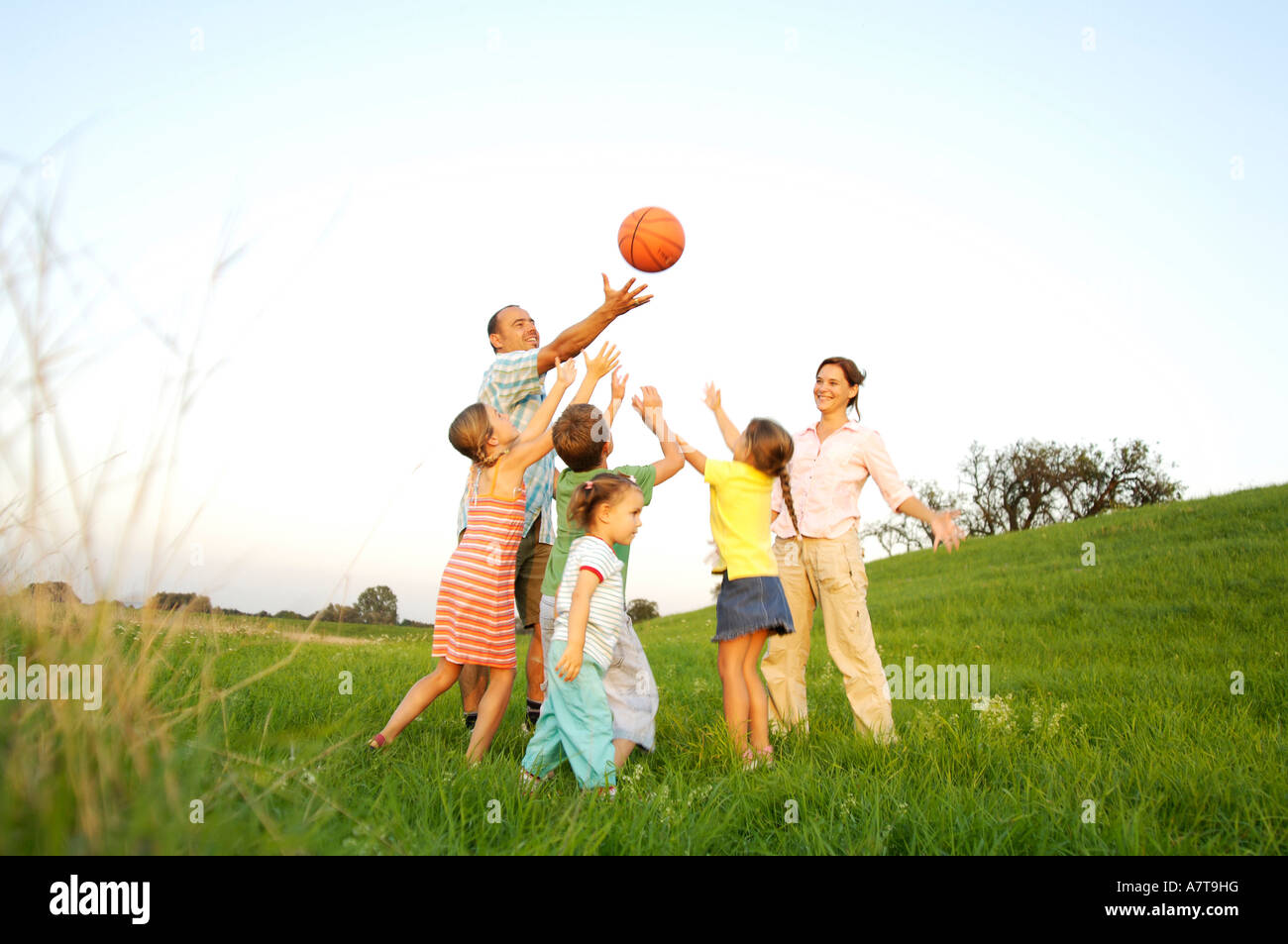 Family playing basketball in field Stock Photo