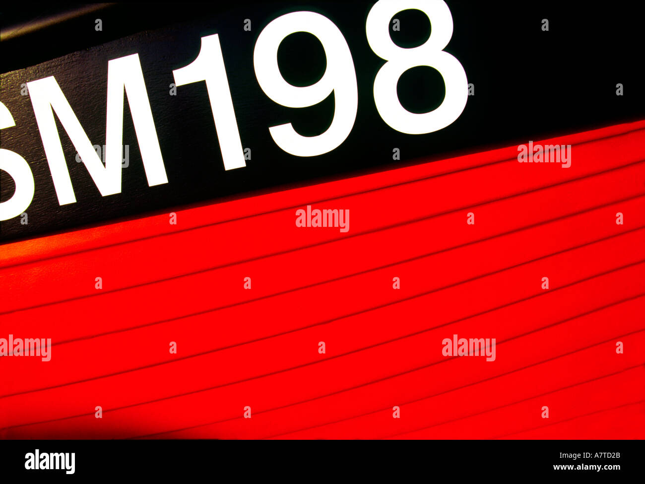 A close up of a red boat showing its registration numbers and letters
